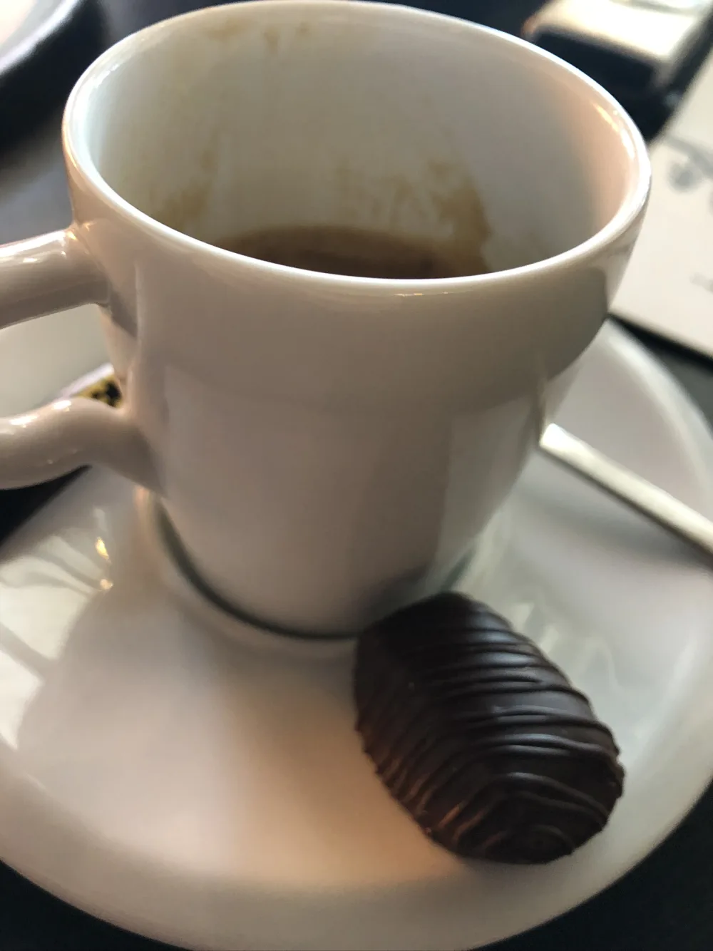 Café dans une tasse blanche accompagné d'un chocolat noir